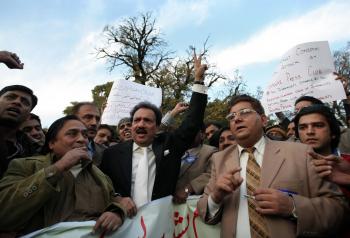 Pakistani Interior Minister Rehman Malik (C) and Pakistani journalists protest against a suicide attack on Peshawar's press club in Islamabad on Dec. 23.  (Behrouz Mehri/AFP/Getty Images)