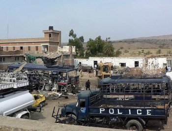 Pakistani security officials stand beside wreckage and a damaged police station building after a suicide bomb attack in Karak, southeast of Peshawar, in February 2010. (Karim Ullah/AFP/Getty Images)
