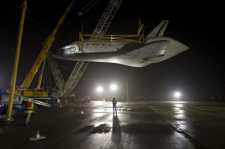 In this handout provided by NASA, the space shuttle Discovery is suspended from a sling held by two cranes shortly after the NASA 747 Shuttle Carrier Aircraft (SCA) was pushed back from underneath at Washington Dulles International Airport, April 19, in Sterling, Virg. Discovery, the first orbiter retired from NASA's shuttle fleet, completed 39 missions, spent 365 days in space, orbited the Earth 5,830 times, and traveled 148,221,675 miles. NASA will transfer Discovery to the National Air and Space Museum to begin its new mission to commemorate past achievements in space and educate and inspire future generations of explorers. (NASA/Bill Ingalls via Getty Images)