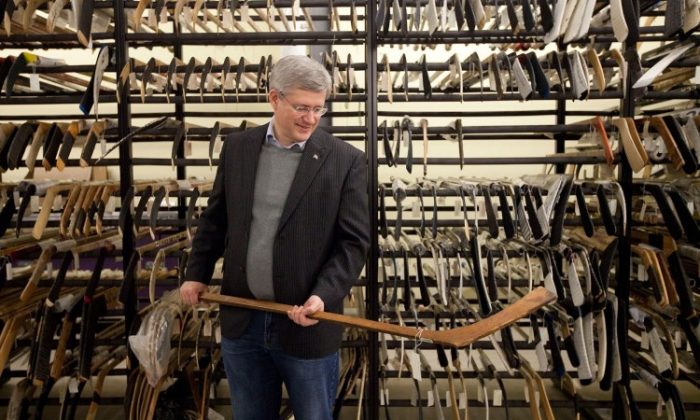 Prime Minister Stephen Harper holds a hockey stick from the 1907 Stanley Cup final during a research visit to the Hockey Hall of Fame in Toronto in December 2011. (Simon and Schuster Canada)
