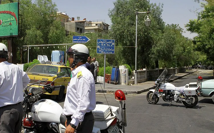 Syrian police guard the road near the scene of the suicide bomb attack that targeted the National Security headquarters in Rawda, a high security district in the heart of the capital, Damascus, on July 18, 2012. (STR/AFP/GettyImages)