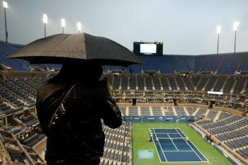 A fan stands under an umbrella as play is suspended due to rain during the men's singles final match between Novak Djokovic of Serbia and Rafael Nadal of Spain on day fifteen of the 2010 U.S. Open at the USTA Billie Jean King National Tennis Center on September 13, 2010 in the Flushing neighborhood of the Queens borough of New York City. (Al Bello/Getty Images)