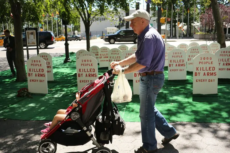 A man and child walk by a mock graveyard across from the United Nations (UN) which represents those killed by arms everyday around the world on July 25, 2012 in New York City. The group Control Arms set up the campaign to help draw attention to the issues of deaths by guns and other armaments while negotiations continue at the UN for a new Arms Trade Treaty. (Spencer Platt/Getty Images)