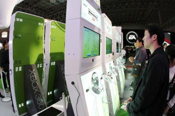 In this file photo, visitors try out games with XBOX 360 at Microsoft Booth in Chiba, Japan. Microsoft is raising prices for its XBox Live service. (Junko Kimura/Getty Images)