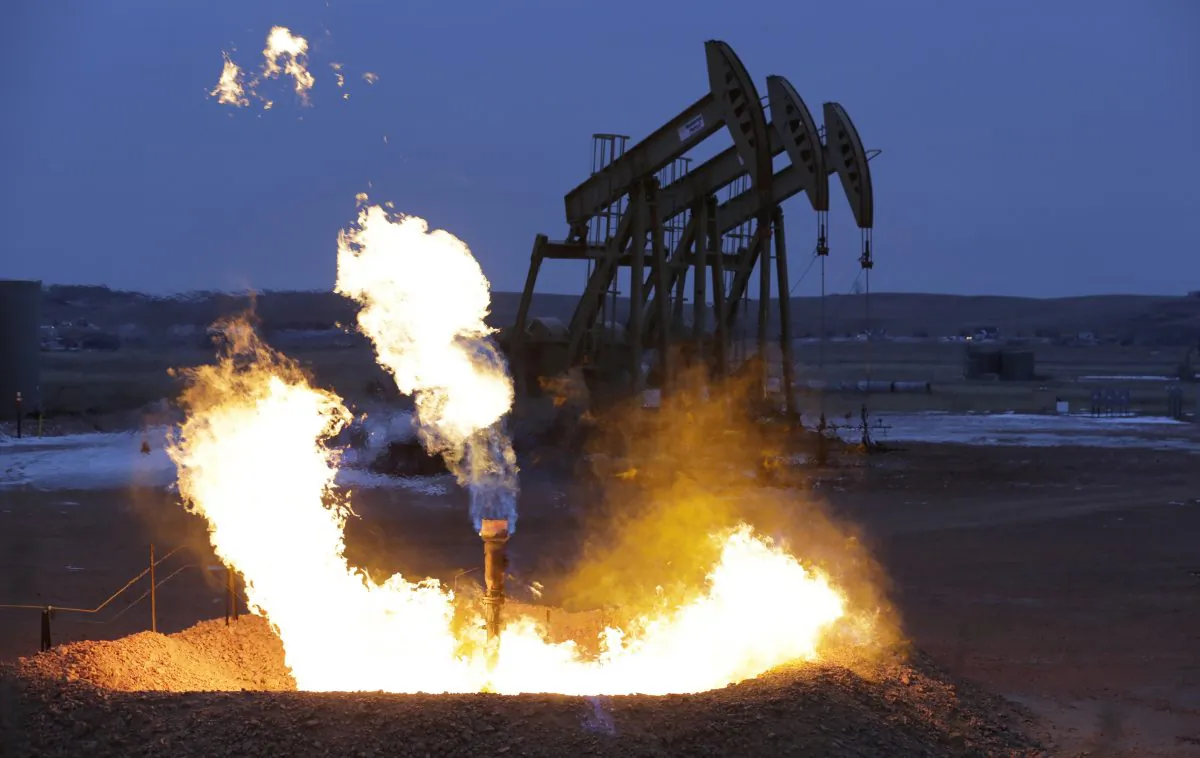 Oil pump jacks work behind a natural gas flare near Watford City, N.D., on Dec. 17, 2014. (Eric Gay/AP Photo)