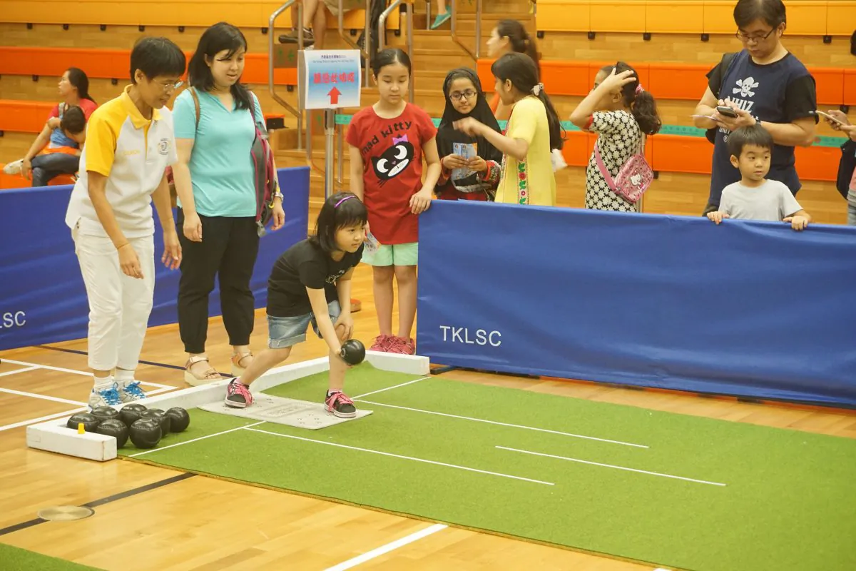 Hong Kong Lawn Bowls Association coach YY Wu teaching kids the basics of lawn bowls at the Sport for All Day event at Tiu Keng Leng Sports Centre on Sunday Aug 2. (Claudius Lam)