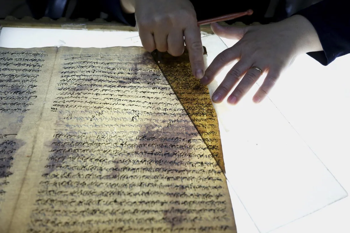 In this Tuesday, July 28, 2015 photo, a member of the library restoration staff works on a damaged document at the Baghdad National Library in Iraq. (AP Photo/Karim Kadim)