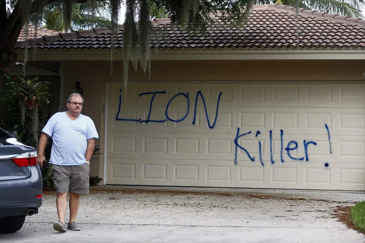 Private Investigator for the Palmer family, Walter Zalisko, of Global Investigative group in Fort Myers walks out of the home Tuesday, Aug. 4, 2015, at the Marco Island home of dentist Walter J. Palmer. Zalisko said no vandalism was found inside. The home was discovered vandalized with the worlds "LION Killer!" and littered with pigs feet drenched in hot sauce. Palmer, a Minnesota resident, is wanted in the killing of Zimbabwe's famous lion, Cecil, a lion who drew thousands of tourists and dollars annually. (Corey Perrine/Naples Daily News via AP)