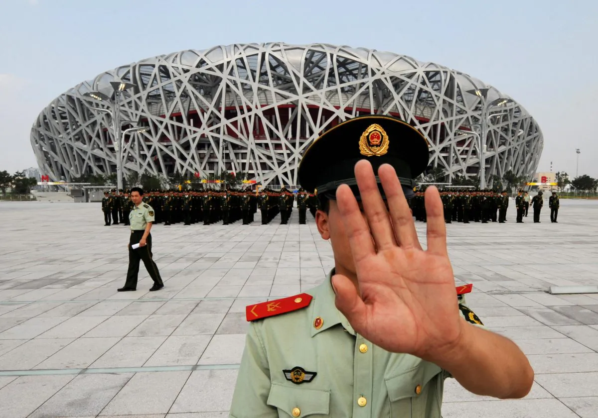 A Chinese paramilitary policeman tries to block photos being taken of a military parade rehearsal, outside the Olympic Stadium in Beijing on July 21. (Mark Ralston/AFP/Getty Images)