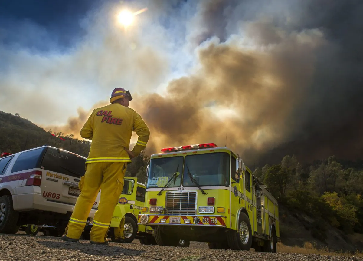Dave Miinch, fire captain with South Lake County, watches a fire burn on the north side of U.S. Highway 20, Monday, August 3, 2015, in Yolo County, Calif. (Hector Amezcua/The Sacramento Bee via AP)