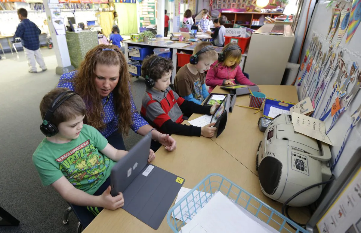 Teacher Haley Fazio works with her kindergarten students on a frog-research lesson viewed on tablet computer in Des Moines, Wash., on March 10, 2015. (AP Photo/Ted S. Warren)