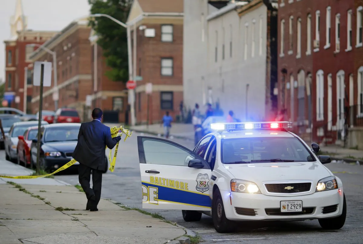 A member of the Baltimore Police Department removes crime scene tape on July 30, 2015, from a corner where a victim of a shooting was discovered. (Patrick Semansky/AP Photo)