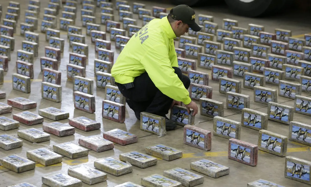 A police officer organizes rows of seized packages of cocaine during a police presentation for the press in Bogota, Colombia, on July 22, 2015. (AP Photo/Fernando Vergara)