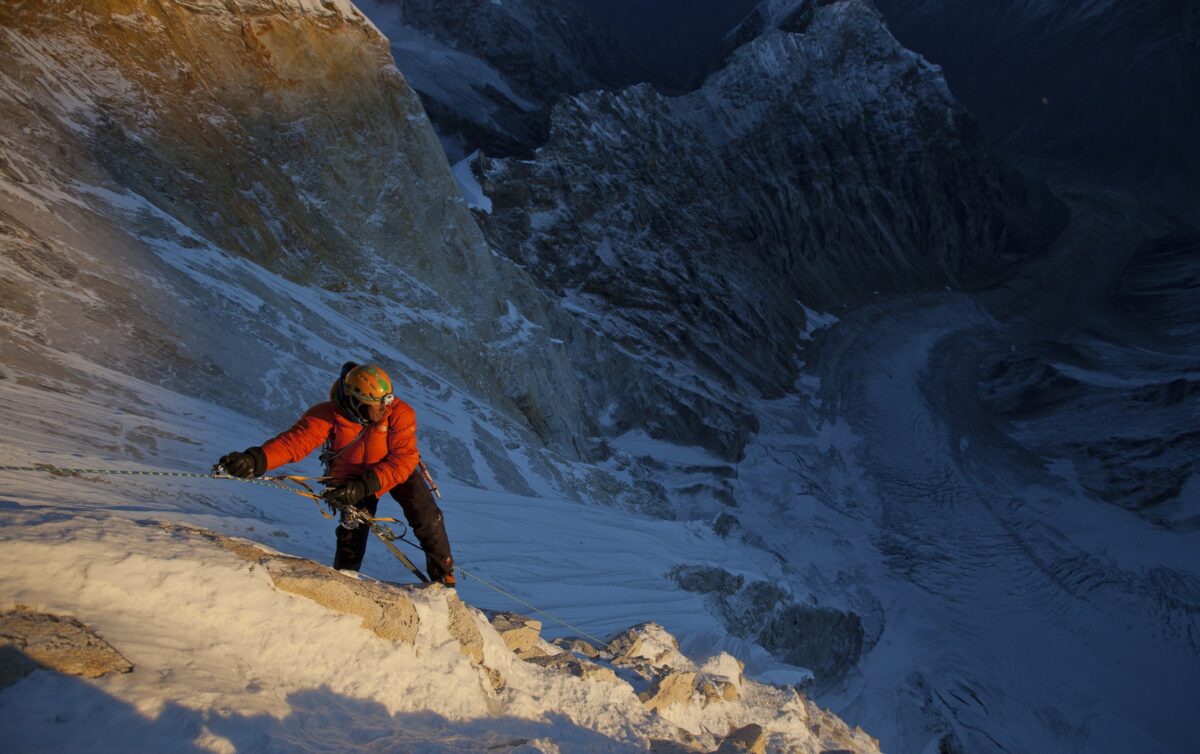 man rappells down mountain face in Meru