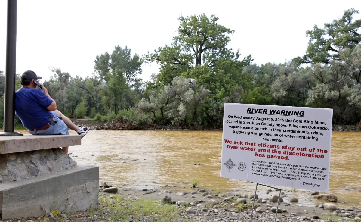 A warning sign from the city is displayed in front of the Animas River as orange sludge from a mine spill upstream flows past Berg Park in Farmington, N.M., Aug. 8, 2015. (Alexa Rogals/The Daily Times via AP)
