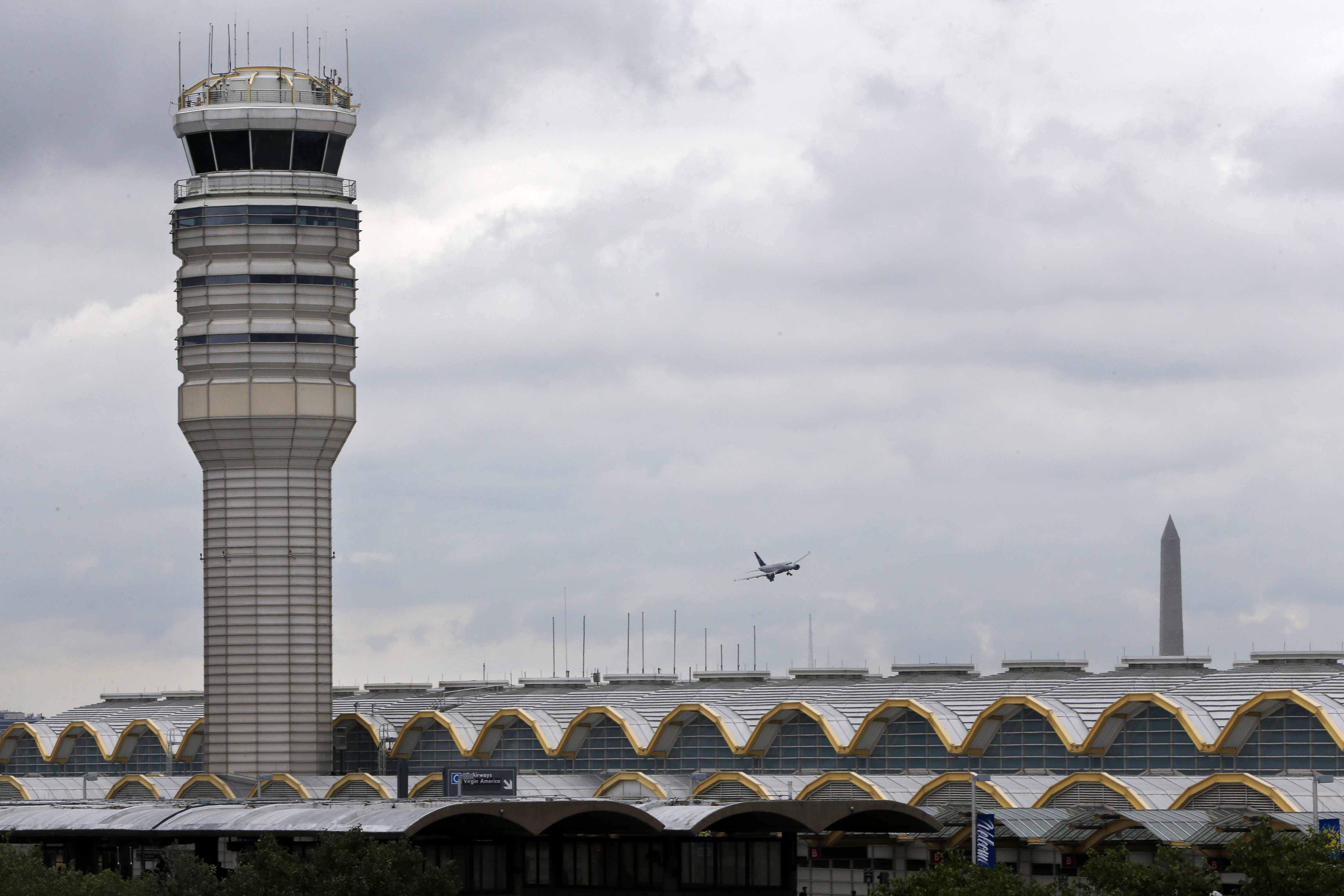 An airplane flies between the air traffic control tower and the Washington Monument at Washington's Ronald Reagan National Airport on Monday, Aug. 10, 2015. For more than three years, the government has kept secret a study it requested that found air traffic controllers work schedules often lead to chronic fatigue, making them less alert and endangering the safety of the national air traffic system, according to report on the study obtained by The Associated Press. (AP Photo/Jacquelyn Martin)
