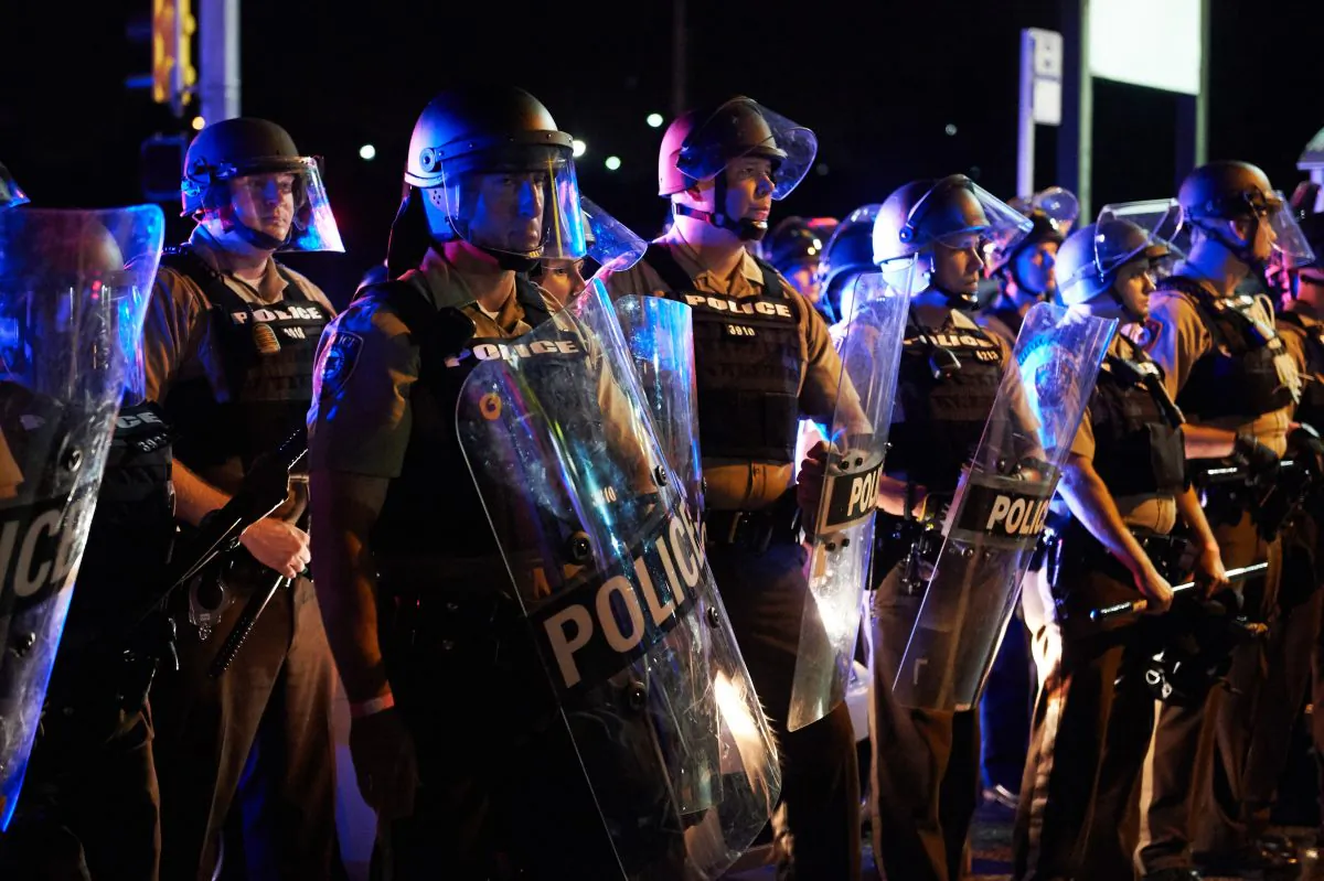 St. Louis County Police and Missouri State Highway Patrol troopers stand guard as protesters march on West Florissant Avenue in Ferguson, Missouri on August 9, 2015. A day of peaceful remembrance marking the anniversary of 18-year-old teen Michael Brown's killing by police in the US city of Ferguson came to a violent end on August 9 as gunfire left at least one protester injured. (Michael B. Thomas/AFP/Getty Images)