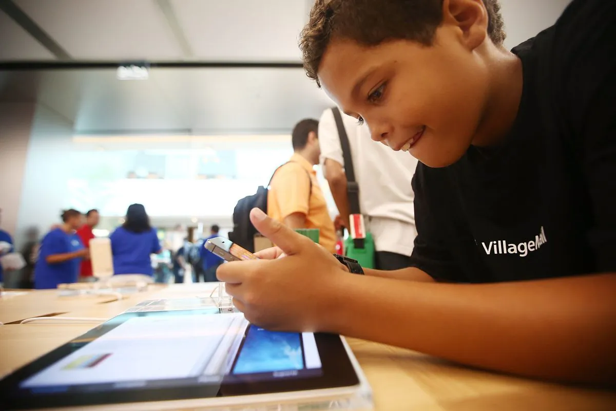 A boy plays with an iPhone in Brazil's first Apple retail store minutes after it opened to the public for the first time in the Village Mall shopping center on February 15, 2014 in Rio de Janeiro, Brazil. (Photo by Mario Tama/Getty Images)