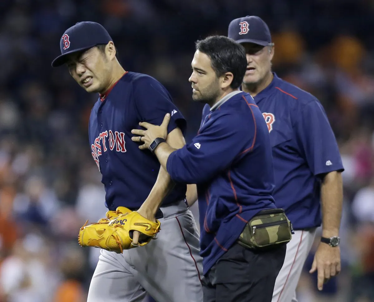Koji Uehara #19 of the Boston Red Sox is led off the field by trainer Brad Pearson, with manager John Farrell following, after taking a line drive off the right wrist from Ian Kinsler of the Detroit Tigers during the ninth inning at Comerica Park on August 7, 2015 in Detroit, Michigan.(Duane Burleson/Getty Images)