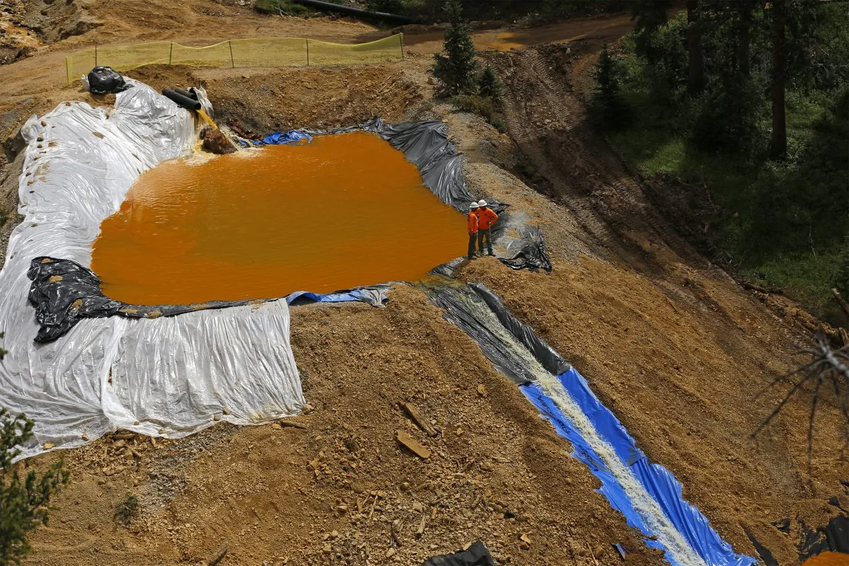 Environmental restoration employees work at a temporary water treatment holding facility at the Gold King Mine north of Silverton, Colo., on Monday, Aug. 10, 2015. (Jon Austria/The Daily Times via AP)