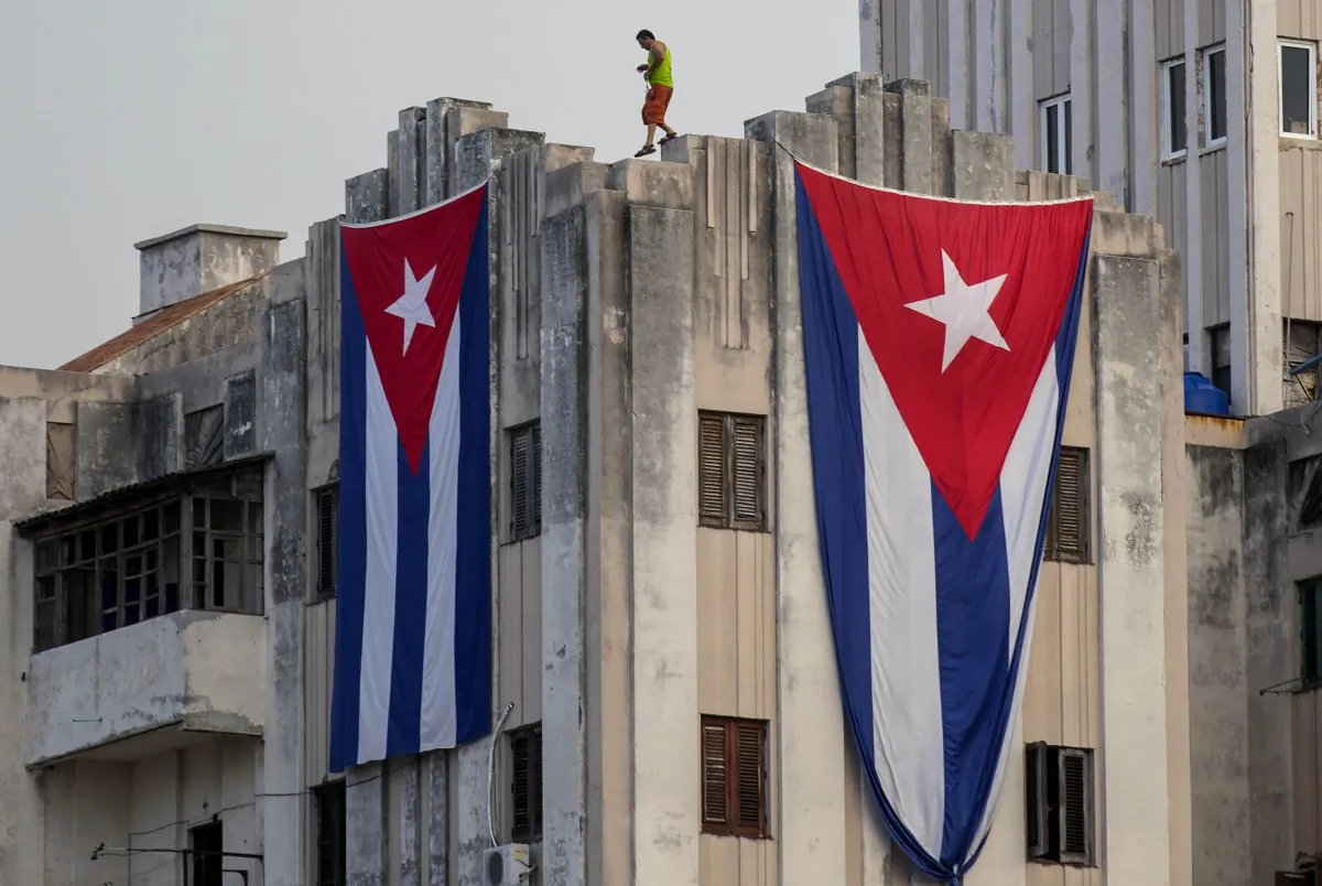 A man walks along the ledge of a building after hanging two giant Cuban flags, next to the US embassy, in Havana, Cuba, on Aug. 11, 2015. (Ramon Espinosa/AP Photo)