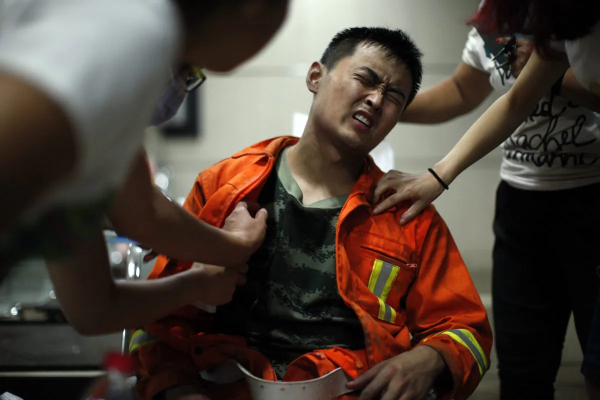 An injured firefighter grimaces as he is examined in a hospital following explosions in northeastern China's Tianjin municipality, Thursday, Aug. 13, 2015. (Chinatopix Via AP) 