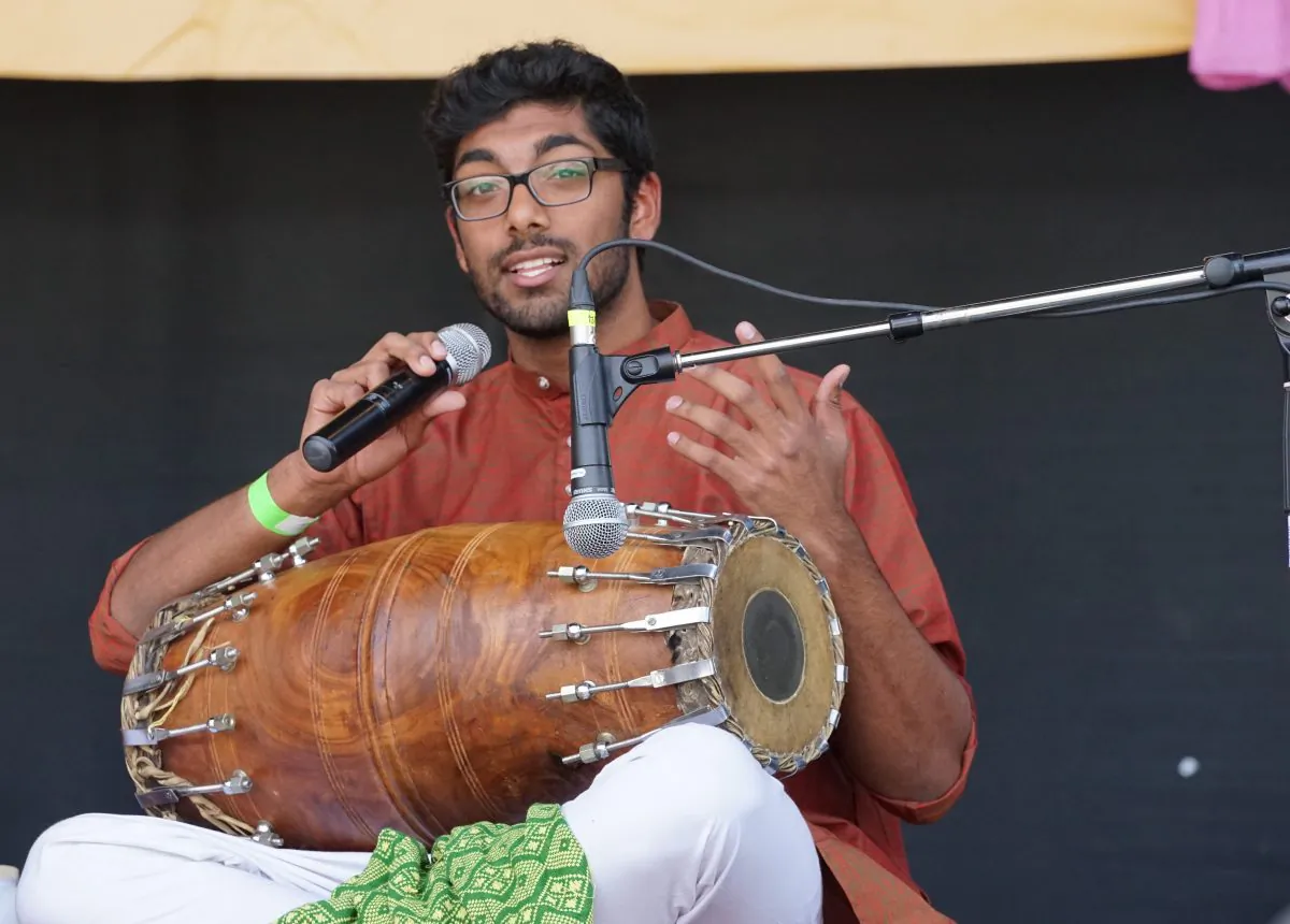 A drummer explains how to play the naal, a wooden drum that requires two-handed playing. (Pam McLennan/Epoch Times)