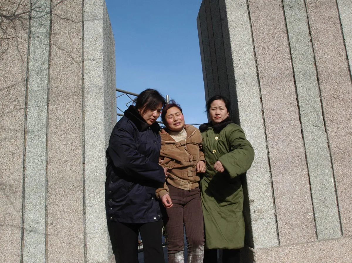 A woman walks out of a building with friends after recognizing the body of her relative who died at the Sunjiawan Coal Mine accident on February 17, 2005 in Fuxin of Liaoning Province, northeast China.  (China Photos/Getty Images)