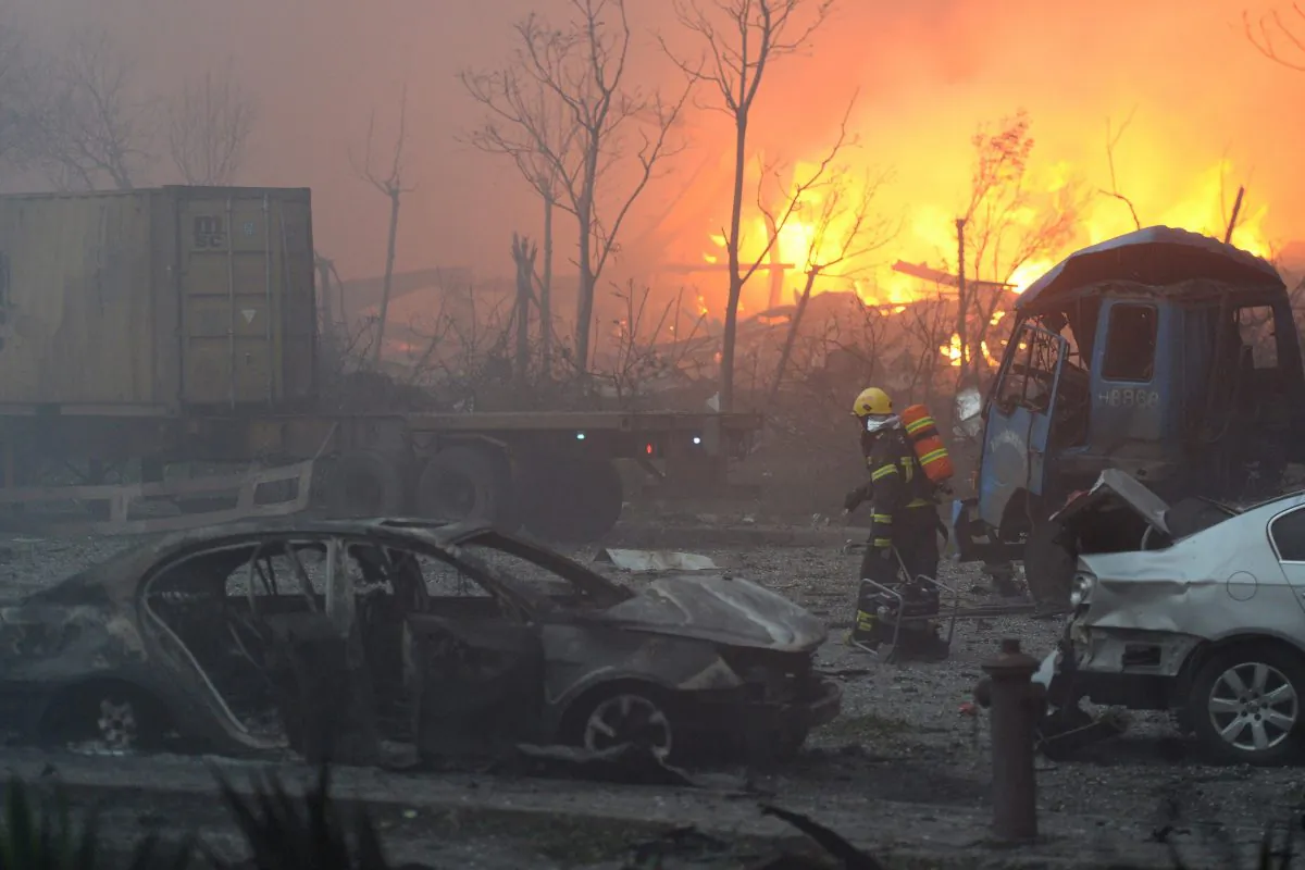 A firefighter walks past damaged vehicles after a series of explosions at a warehouse hit the city of Tianjin on August 13, 2015. (STR/AFP/Getty Images)