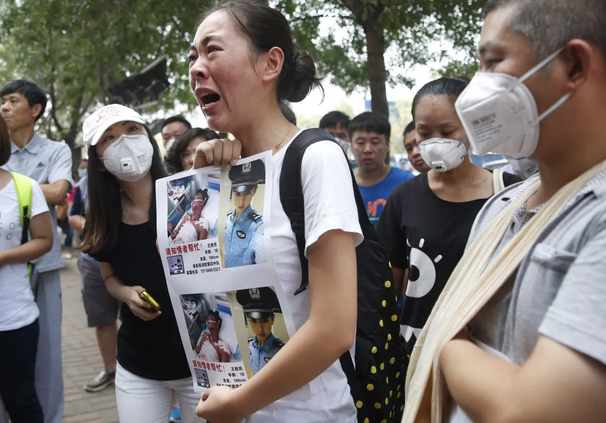 A family member (C) of a missing firefighter from the recent explosions at a chemical warehouse protests outside a hotel where authorities are holding a press conference in Tianjin, China, on August 16. (STR/AFP/Getty Images)