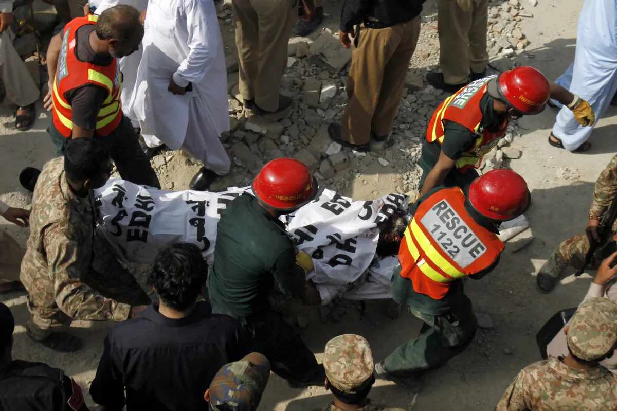 Pakistani rescue workers carry a dead body after recovering it from the rubble at the site of suicide bombing in Shadi Khan, some 80 kilometers (50 miles) northwest from Pakistani capital, Sunday, Aug. 16, 2015. (AP Photo/Anjum Naveed)