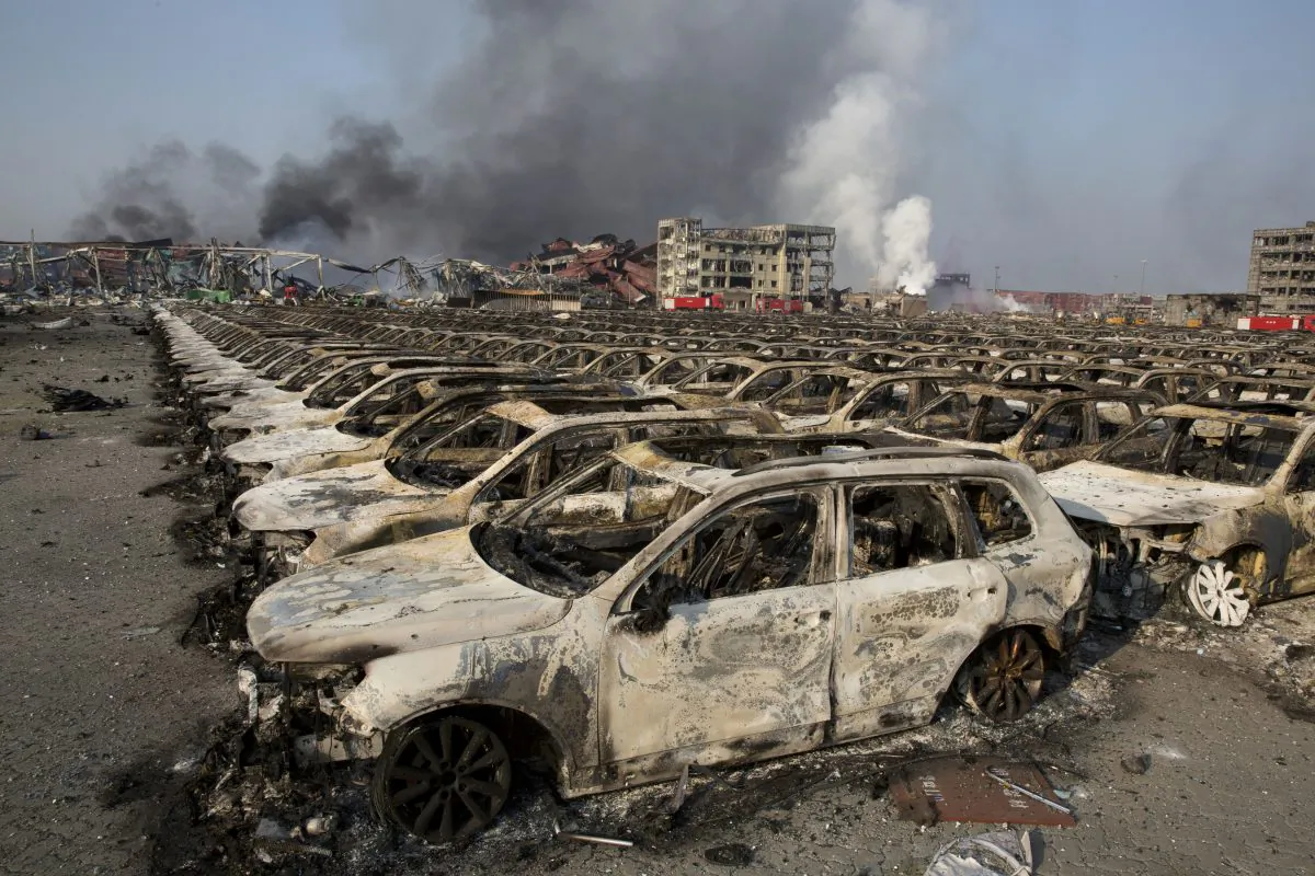 Smoke billows from the site of an explosion that reduced a parking lot filled with new cars to charred remains at a warehouse in northeastern China's Tianjin municipality, Thursday, Aug. 13, 2015. (AP Photo/Ng Han Guan)