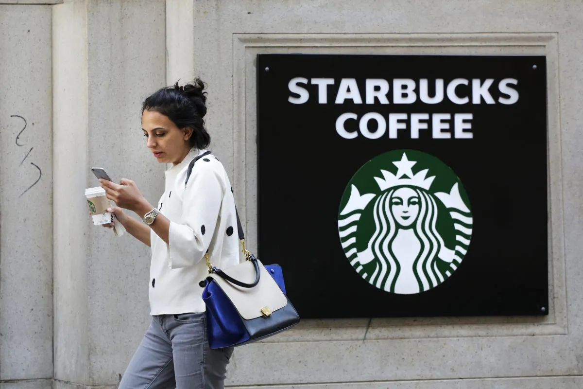 In this July 16, 2015, file photo, a woman walks out of a Starbucks Coffee with a beverage in hand in New York. (AP Photo/Mark Lennihan)