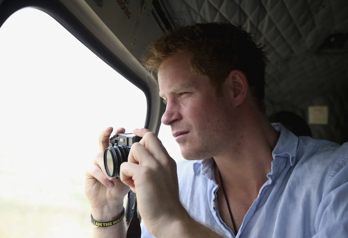Prince Harry takes a photograph out of the window of a helicopter as he travels over the Muluti Mountains on his way to visit a herd boy night school constructed by his Sentebale charity, in Mokhotlong, Lesotho, on Dec 8, 2014. (Chris Jackson/AP)