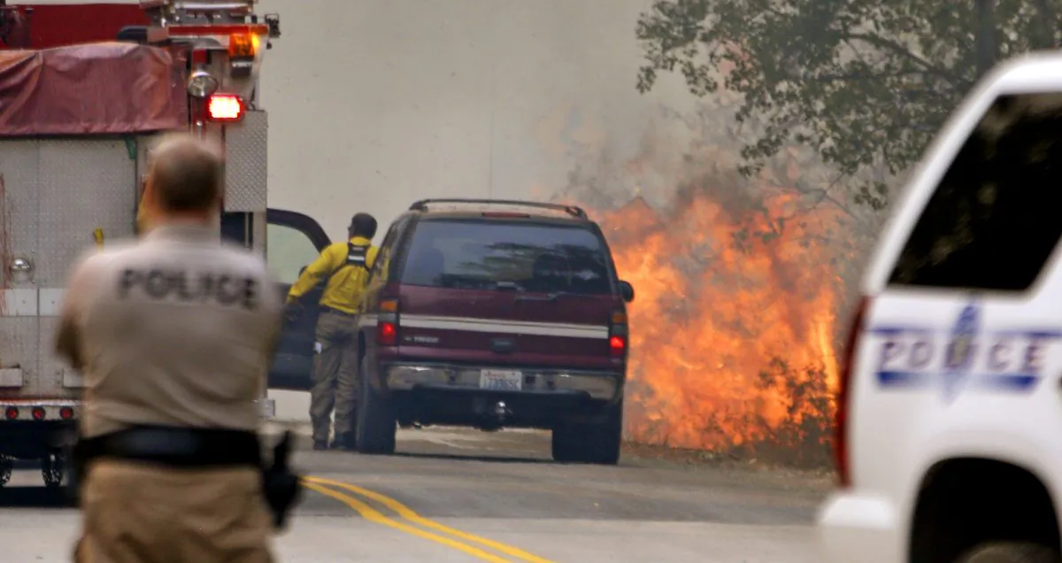 Flames kick up beside a road as firefighters respond to the flare-up Thursday, Aug. 20, 2015, in Twisp, Wash, a day after three firefighters were killed fighting a wildfire near the town. (AP Photo/Elaine Thompson)