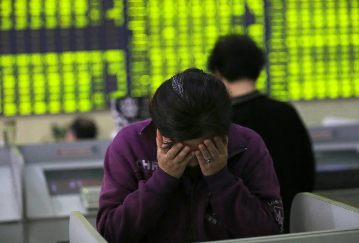 A woman rubs her face as she stands at a computer terminal in a stock brokerage house in Nantong in eastern China's Jiangsu Province, on July 8, 2015. (Chinatopix via AP)
