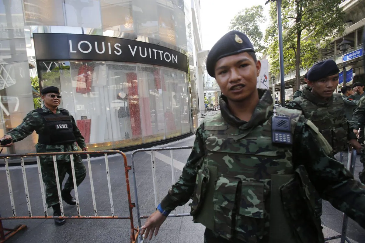 Soldiers move onlookers back from the shattered windows of a Louis Vuitton shop at Gaysorn shopping plaza across from the Erawan Shrine at Rajprasong intersection after a bombing in Bangkok, Thailand, on Aug. 18, 2015. (AP Photo/Sakchai Lalit)