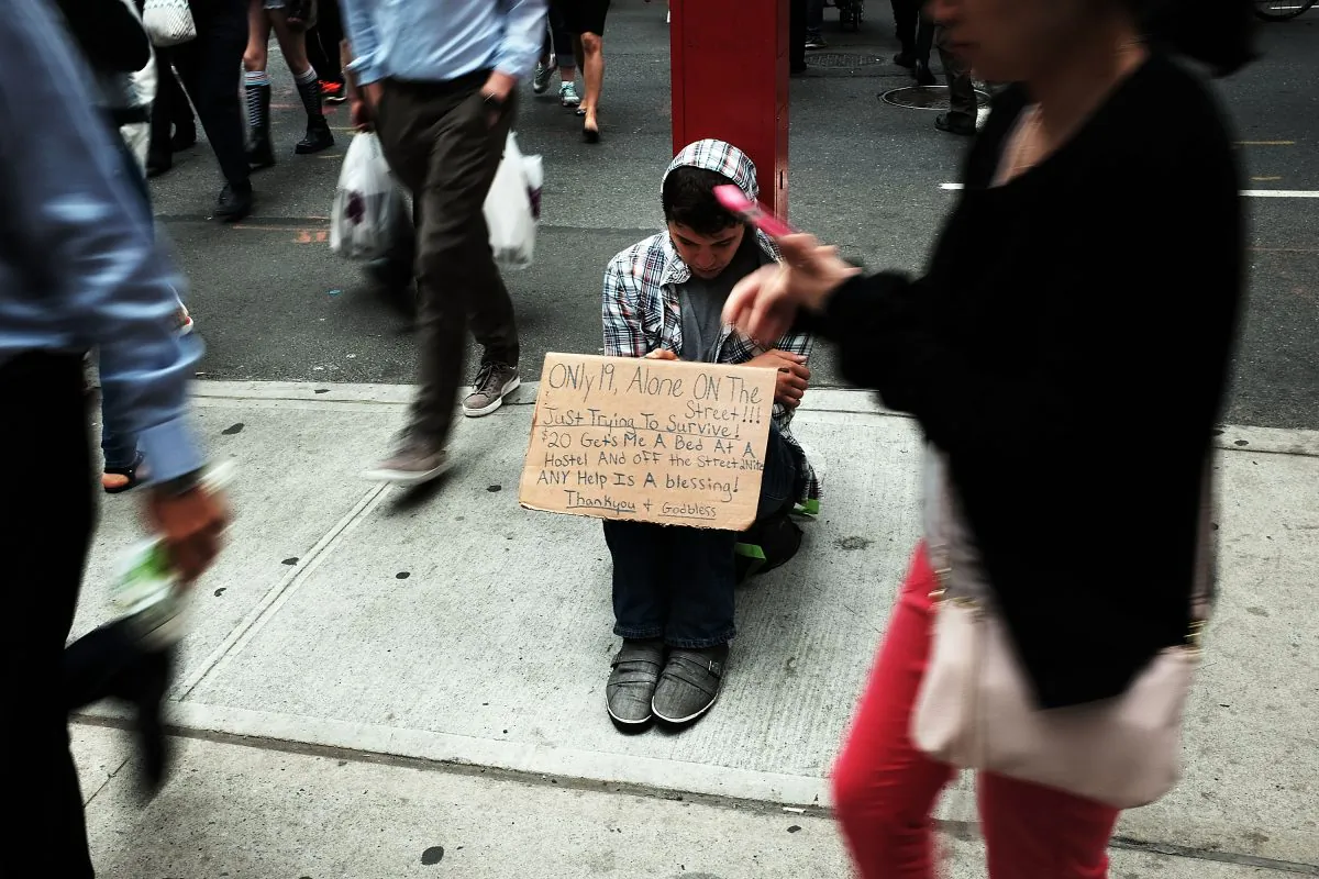 A homeless teen panhandles on a street near Eighth Avenue in Manhattan on May 18, 2015 in New York City. ( Spencer Platt/Getty Images)