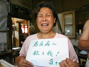 Jiang Caiyu, 48, cries while showing a sign which reads "I am a cancer patient, save me" at her house in Shanghai, on a site scheduled for demolition by Shanghai business mogul Zhou Zhenyi. (Liu Jin/AFP/Getty Images)