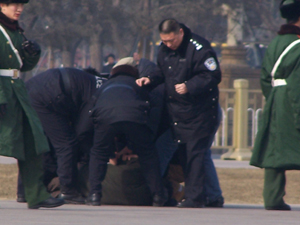 Police beat a man while shielding onlookers from seeing. (Minghui Net) Police beat a man while shielding onlookers from seeing. (Minghui Net)