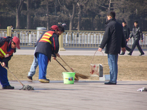 Workers wash away the blood stains. Their portable trash bins are covered with blood. (Minghui Net) Workers wash away the blood stains. Their portable trash bins are covered with blood. (Minghui Net)