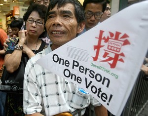 A man holds a pro-democracy banner as he waits for the thousands of fellow protesters to pass. (Ted Aljibe/AFP/Getty Images)