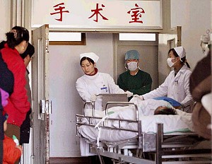 Family members watch as nurses wheel a patient into a hospital in China. (AFP/AFP/Getty Images)