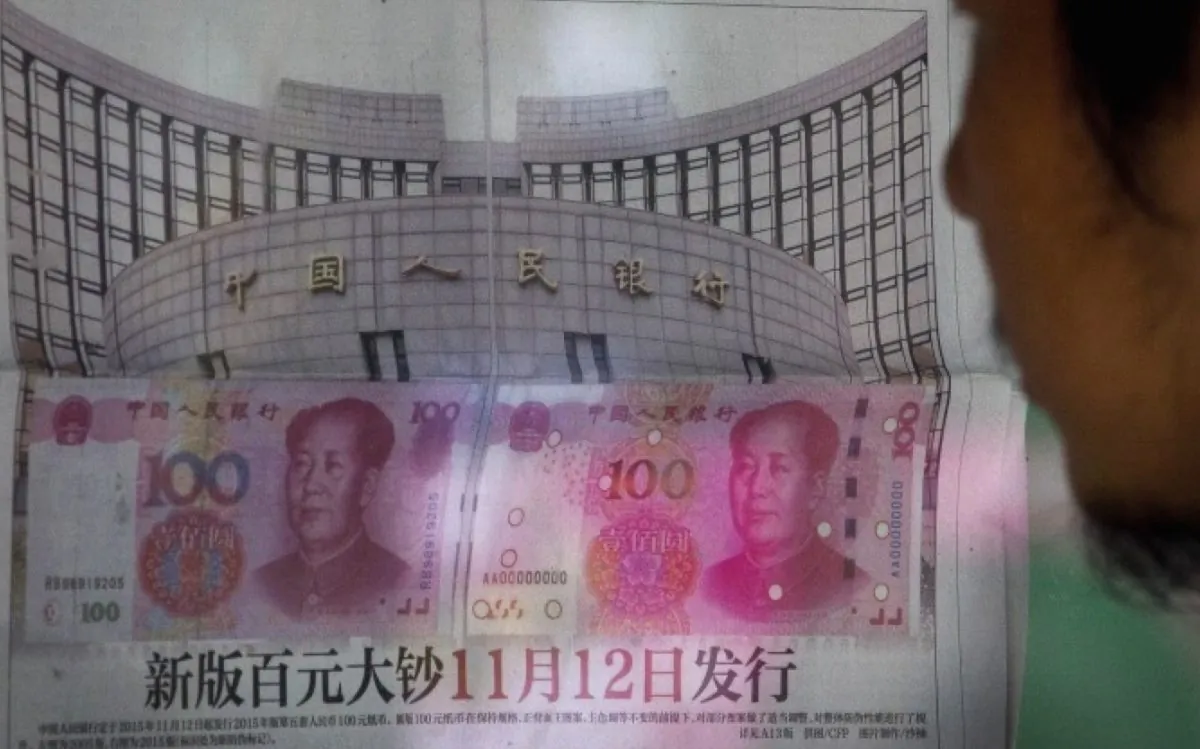 A man reads a newspaper report that China's central bank announced it will devalue China's tightly controlled currency on Aug. 11, 2015 following a slump in trade, triggering the yuan's biggest one-day decline in a decade. (AP Photo/Andy Wong)