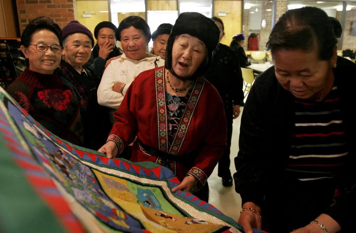 Hmong immigrants take a look at a Hmong story cloth that promotes seasonal safety tips at the Volunteers of America building, in Minneapolis, Minn., on Dec. 7, 2005. (AP Photo/Beth Schlanker)