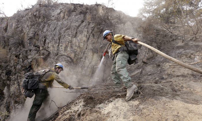 University of Alaska, Fairbanks, firefighting students Casey Lasota, left, and Harold Stein work to cool hotspots left from a wildfire Sunday, Aug. 23, 2015, in Chelan, Wash. (AP Photo/Elaine Thompson)