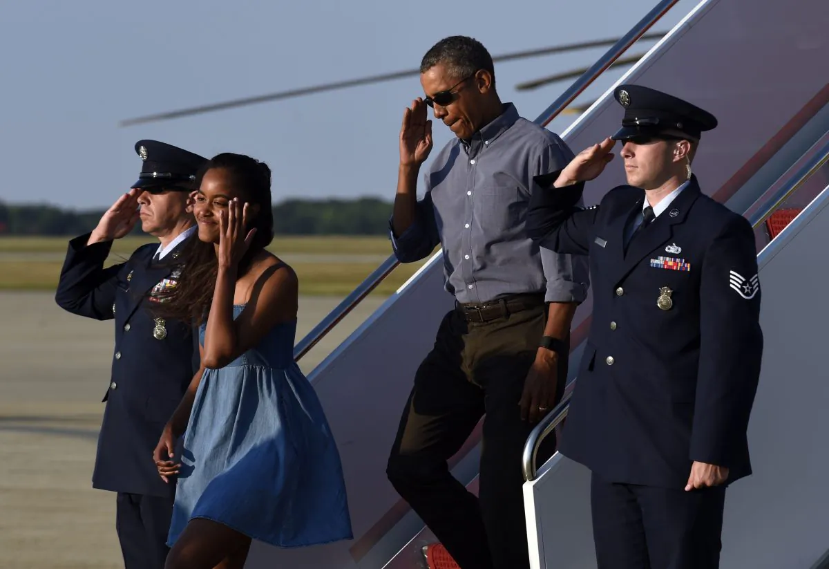 President Barack Obama salutes as he walks off of Air Force One with his daughter Malia at Andrews Air Force Base in Md., Sunday, Aug. 23, 2015. The president is returning to Washington after he and his family spent more than two weeks vacationing on the Massachusetts island of Martha's Vineyard. (AP Photo/Susan Walsh)