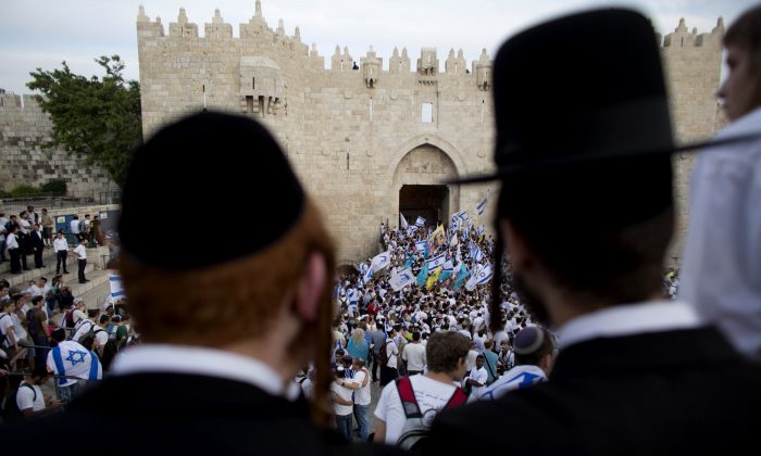 Ultra-Orthodox Jews watch people wave Israeli flags outside the Damascus Gate during Jerusalem Day celebrations in Jerusalem on May 28, 2014. (Dusan Vranic/AP Photo)