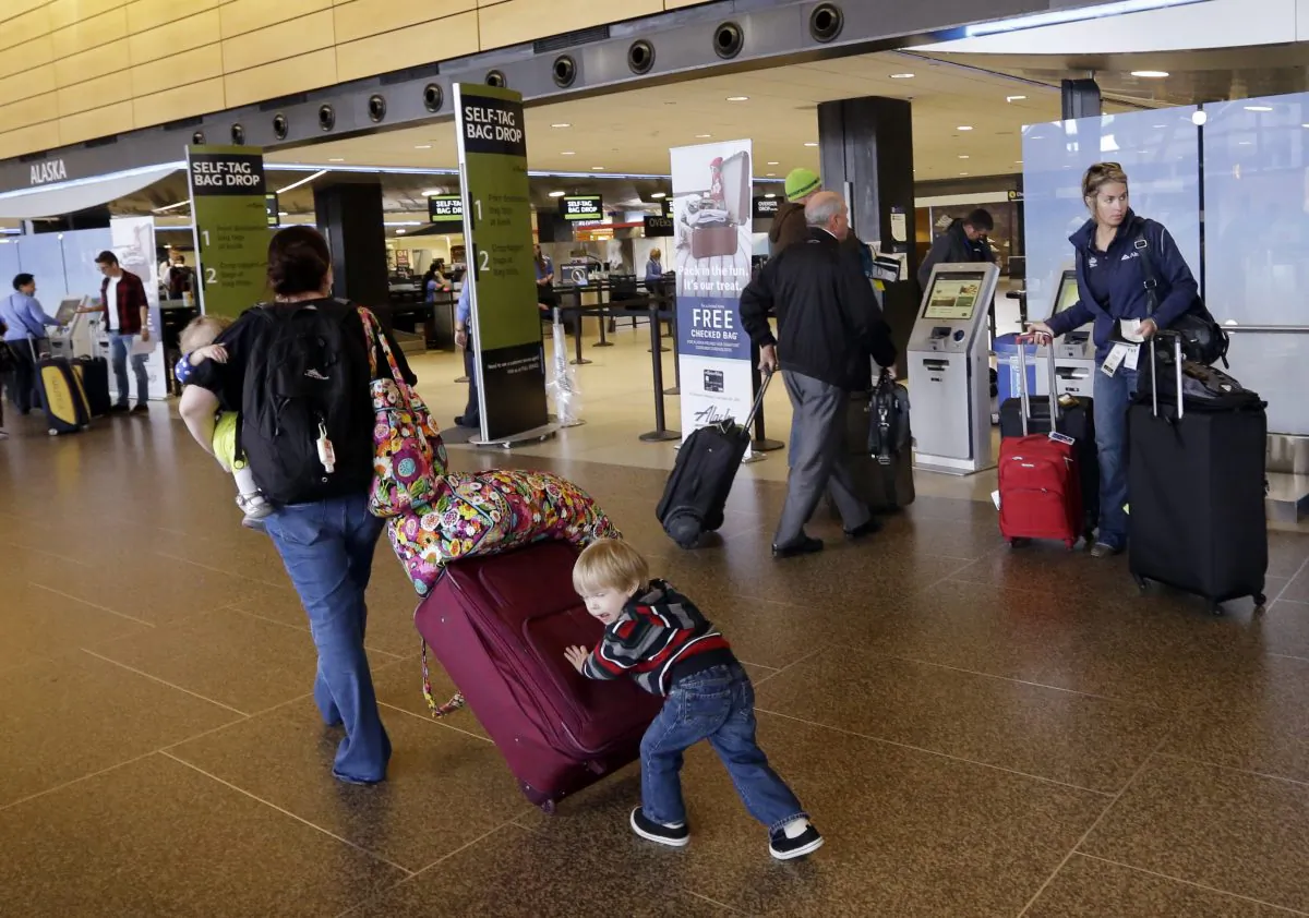 Colin Drummond, 4, pushes luggage from behind as he walks with family members to check-in a relative for an Alaska Airlines flight at Seattle-Tacoma International Airport in SeaTac, Wash., on March 24, 2015. (Elaine Thompson/AP Photo)