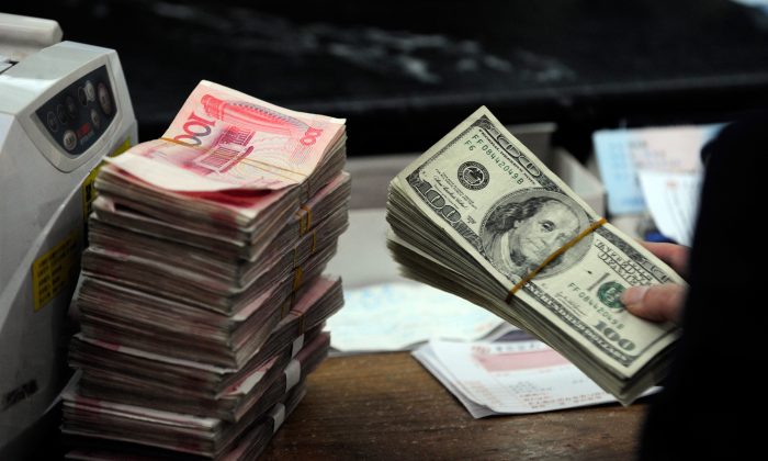 A Chinese bank worker prepares to count a stack of US dollars together with stacks of 100 Chinese yuan notes at a bank in Hefei, Anhui Province, on March 9, 2010. (STR/AFP/Getty Images)